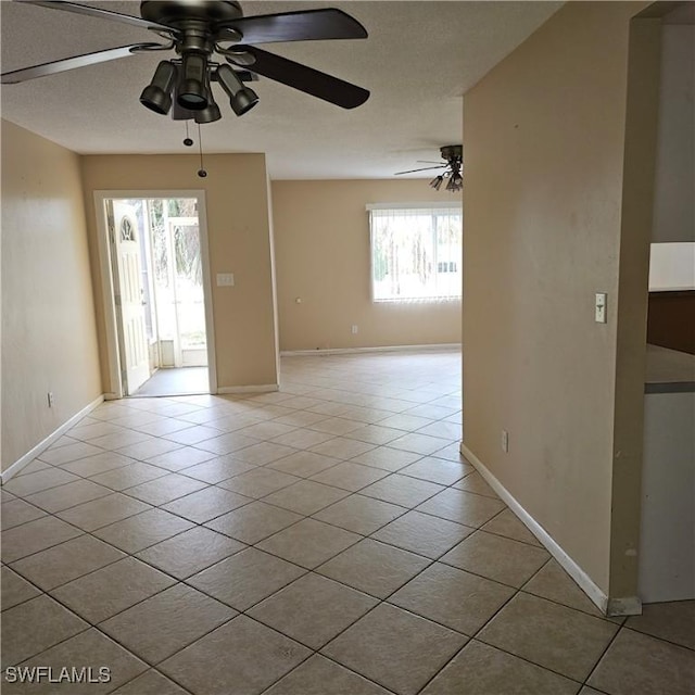 tiled empty room with a wealth of natural light and ceiling fan