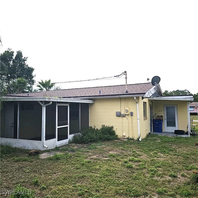 rear view of house with a yard and a sunroom