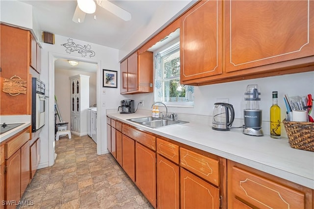 kitchen featuring black electric stovetop, ceiling fan, sink, independent washer and dryer, and oven