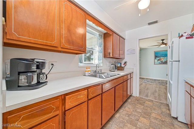 kitchen featuring white refrigerator, ceiling fan, and sink