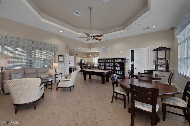 tiled dining space with a towering ceiling, ceiling fan, and a tray ceiling