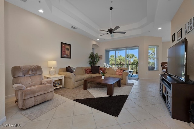 tiled living room featuring a raised ceiling and ceiling fan