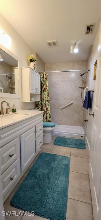 bathroom with toilet, tile patterned flooring, vanity, and walk in shower