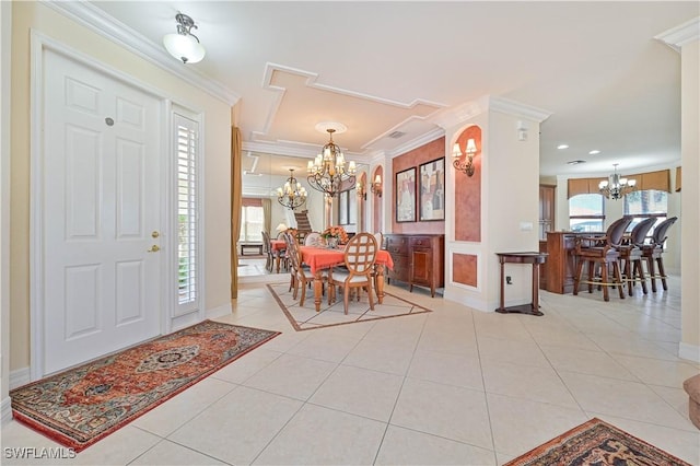 tiled entryway with an inviting chandelier and crown molding