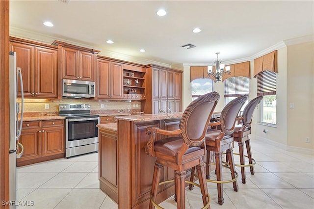 kitchen featuring a chandelier, appliances with stainless steel finishes, a center island, crown molding, and pendant lighting