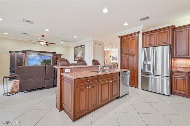 kitchen featuring stainless steel appliances, sink, crown molding, and an island with sink