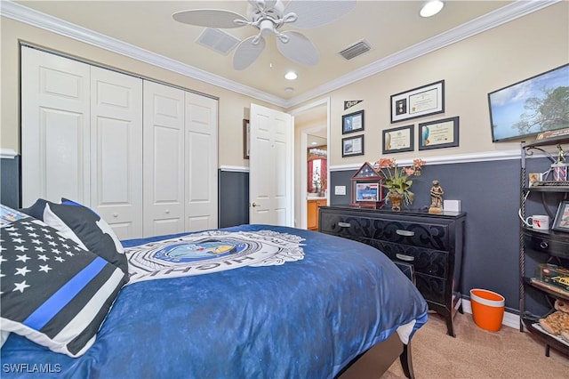 carpeted bedroom with ceiling fan, a closet, and crown molding