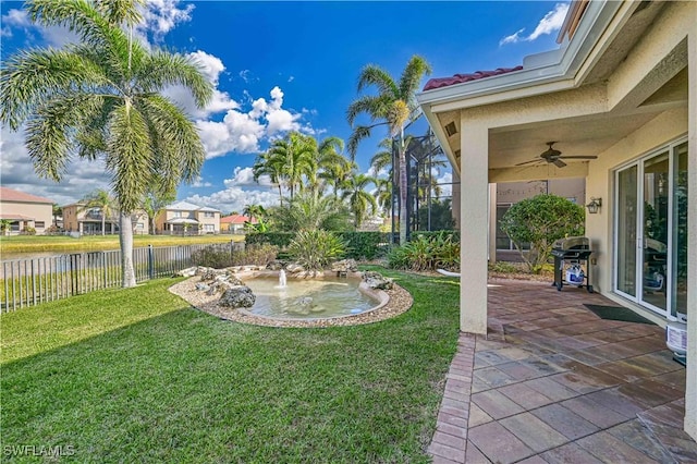 view of yard with ceiling fan, a lanai, a water view, and a patio area