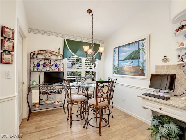 dining room with a fireplace, light wood-type flooring, vaulted ceiling, and a notable chandelier