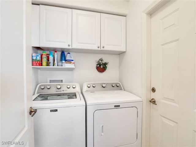 clothes washing area featuring washer and dryer and cabinets