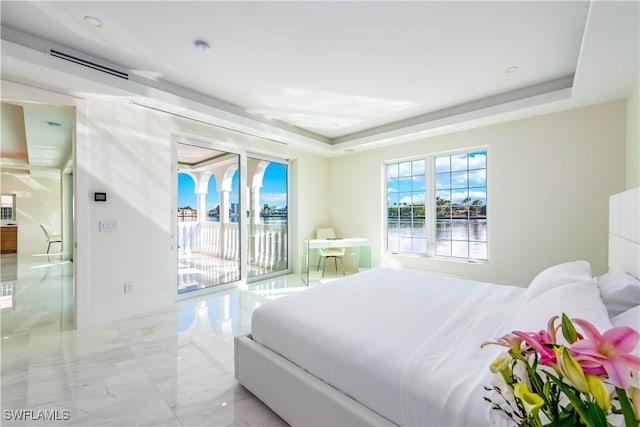 bedroom with access to outside and a tray ceiling