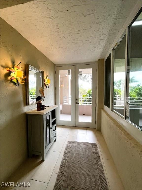 doorway featuring french doors, light tile patterned floors, and a textured ceiling