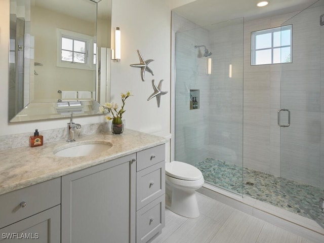 bathroom featuring an enclosed shower, vanity, toilet, and plenty of natural light