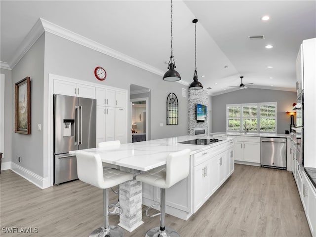 kitchen with lofted ceiling, a center island, appliances with stainless steel finishes, white cabinets, and light stone counters