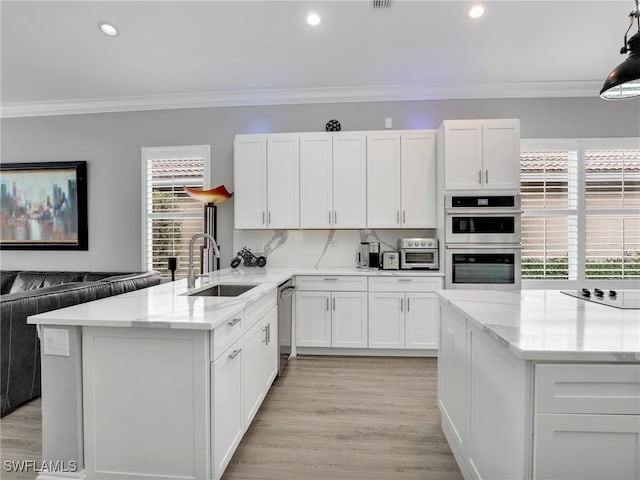 kitchen with kitchen peninsula, sink, appliances with stainless steel finishes, ornamental molding, and white cabinets