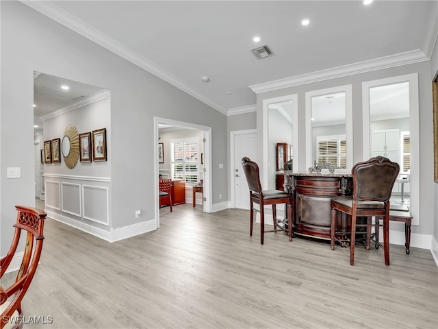 interior space with light hardwood / wood-style floors, bar area, lofted ceiling, and ornamental molding