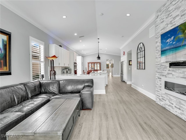 living room featuring light hardwood / wood-style floors, a fireplace, ornamental molding, and vaulted ceiling