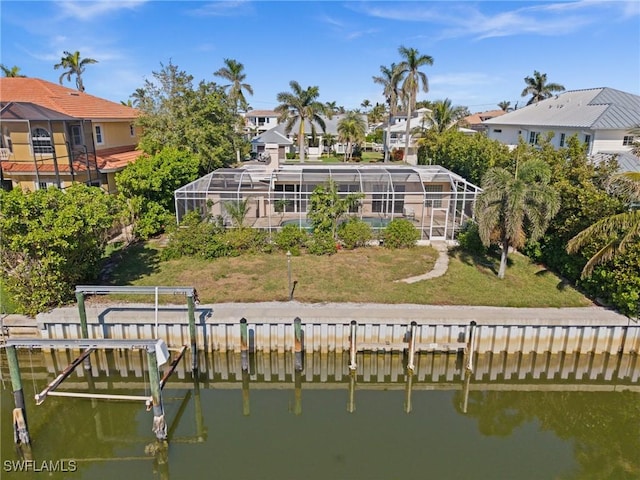 back of house with a lanai, a yard, and a water view