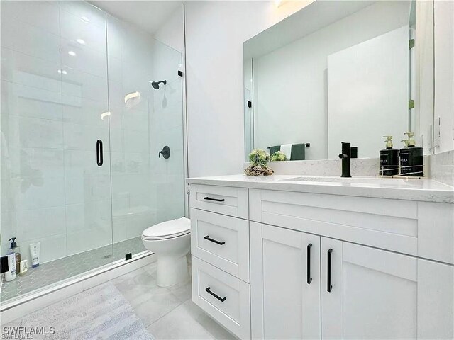 bathroom featuring vanity, toilet, and a shower with door