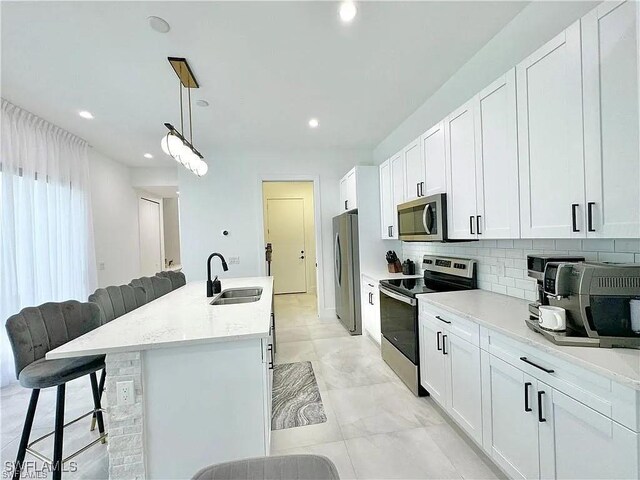 kitchen with appliances with stainless steel finishes, white cabinetry, and hanging light fixtures