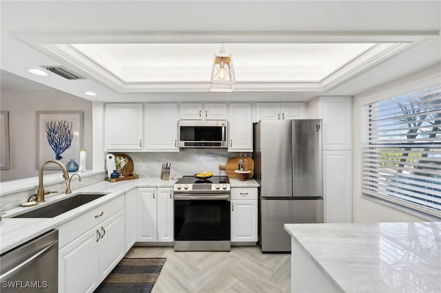 kitchen featuring white cabinets, sink, appliances with stainless steel finishes, and a tray ceiling