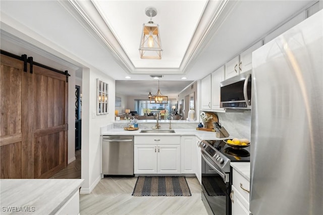 kitchen with white cabinetry, sink, hanging light fixtures, stainless steel appliances, and a barn door