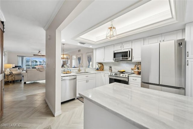 kitchen with stainless steel appliances, light parquet floors, sink, a barn door, and white cabinetry