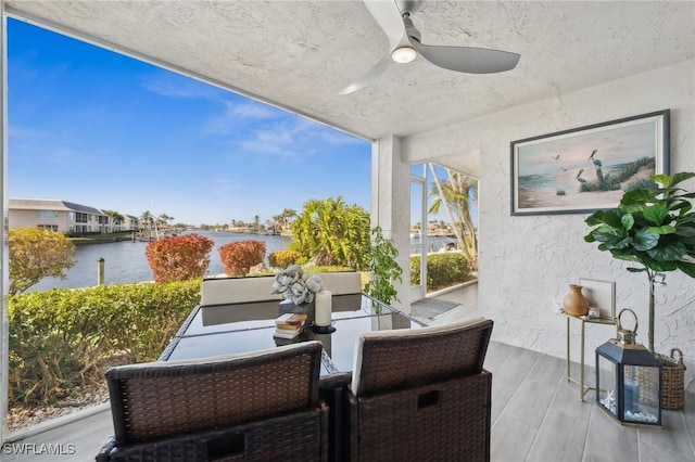 balcony with ceiling fan and a water view