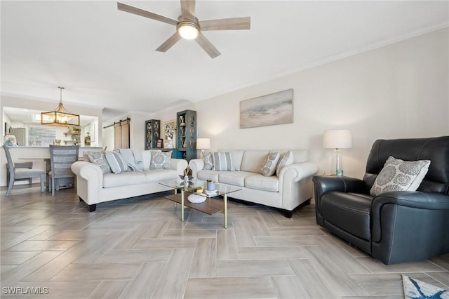 living room featuring ceiling fan with notable chandelier, a barn door, parquet floors, and crown molding