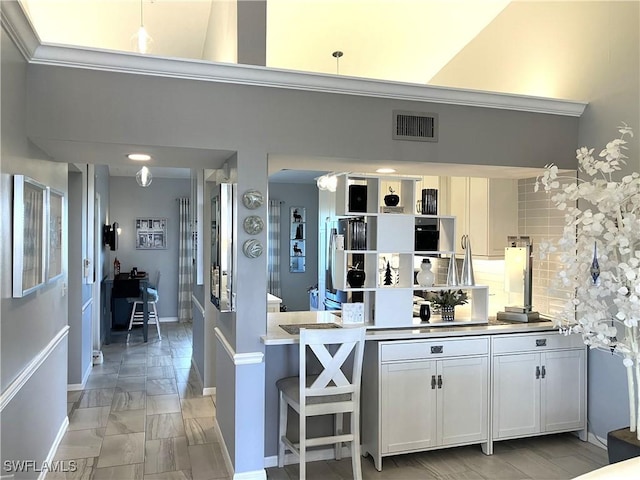 kitchen with visible vents, a towering ceiling, decorative backsplash, and white cabinetry