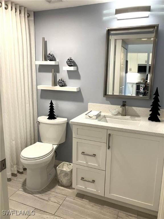 bathroom featuring visible vents, vanity, and toilet