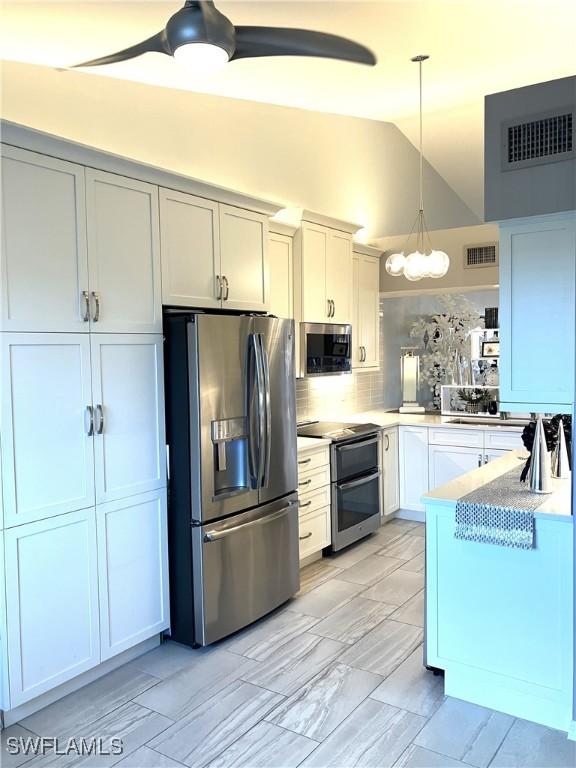 kitchen with stainless steel appliances, white cabinetry, vaulted ceiling, decorative backsplash, and hanging light fixtures