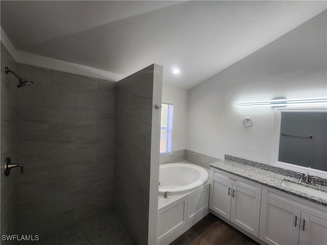 bathroom featuring hardwood / wood-style floors, vanity, plus walk in shower, and vaulted ceiling