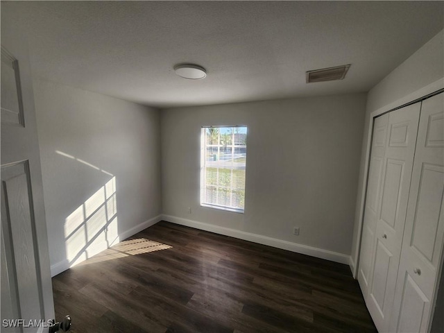 unfurnished bedroom featuring dark hardwood / wood-style flooring and a closet