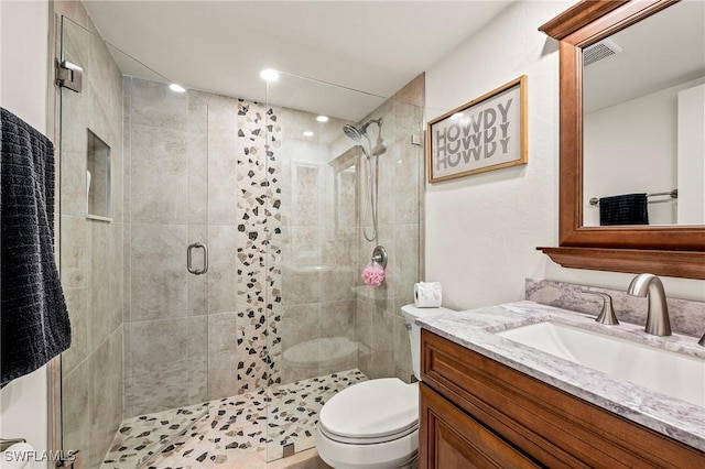 bathroom featuring vanity, a shower with shower door, and toilet