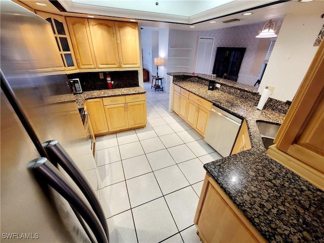 kitchen with dark stone counters, stainless steel appliances, a raised ceiling, light tile patterned floors, and hanging light fixtures