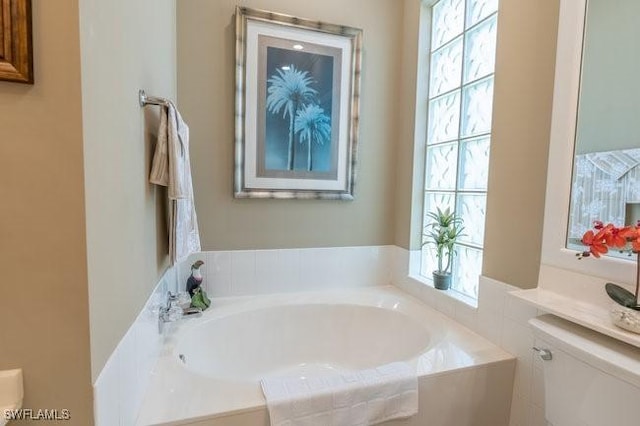 bathroom with tiled bath and a healthy amount of sunlight