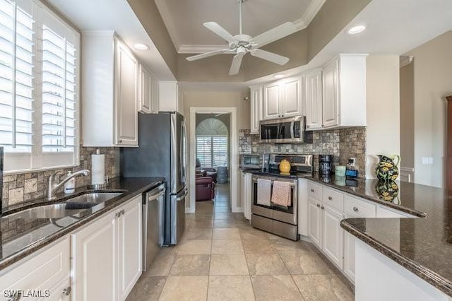 kitchen featuring white cabinets, decorative backsplash, stainless steel appliances, and dark stone counters