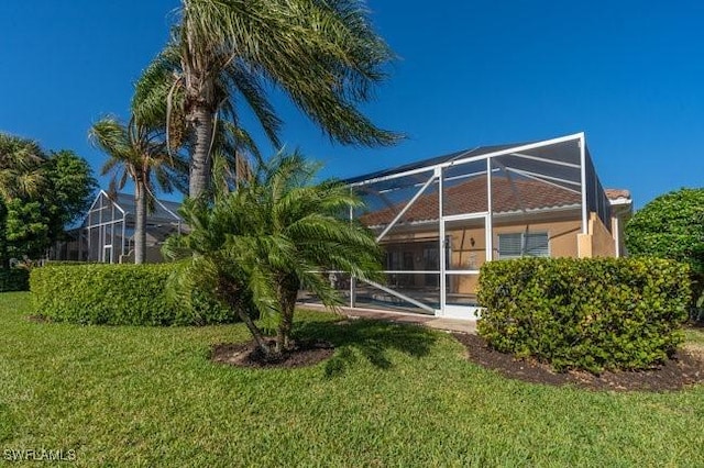 rear view of property with a lanai and a yard