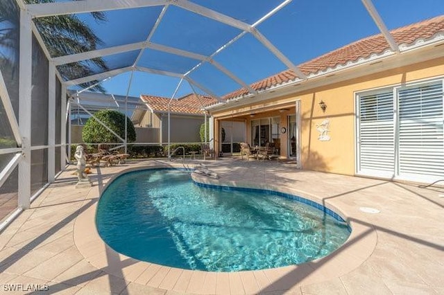 view of swimming pool with glass enclosure and a patio