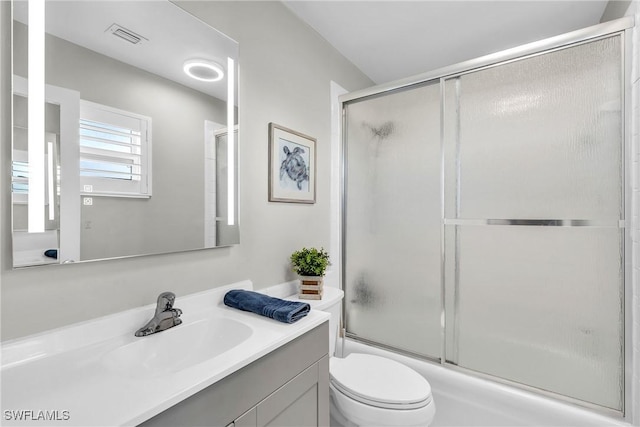 full bathroom with vanity, toilet, and combined bath / shower with glass door