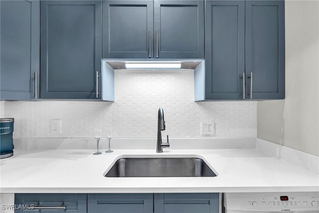 kitchen with white dishwasher, sink, backsplash, and blue cabinetry