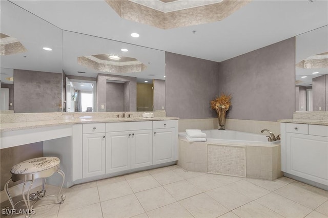 bathroom featuring vanity, a tray ceiling, tile patterned floors, and a relaxing tiled tub