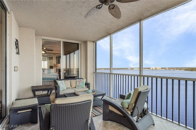 sunroom with ceiling fan and a water view