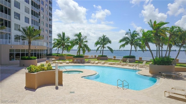 view of swimming pool featuring a community hot tub, a water view, and a patio area