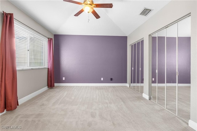 unfurnished bedroom featuring ceiling fan, lofted ceiling, light carpet, and multiple closets