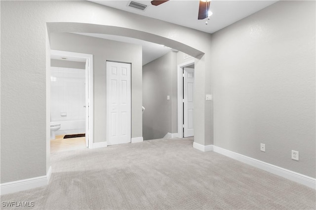 unfurnished bedroom with ensuite bathroom, a closet, ceiling fan, and light colored carpet