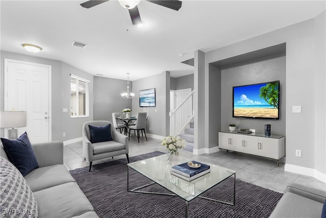 living room featuring light tile patterned flooring and ceiling fan with notable chandelier