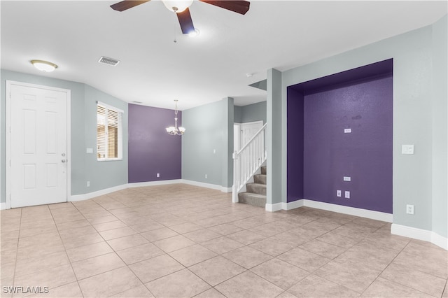 tiled empty room featuring ceiling fan with notable chandelier