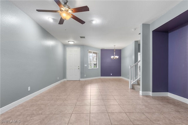 tiled empty room with ceiling fan with notable chandelier